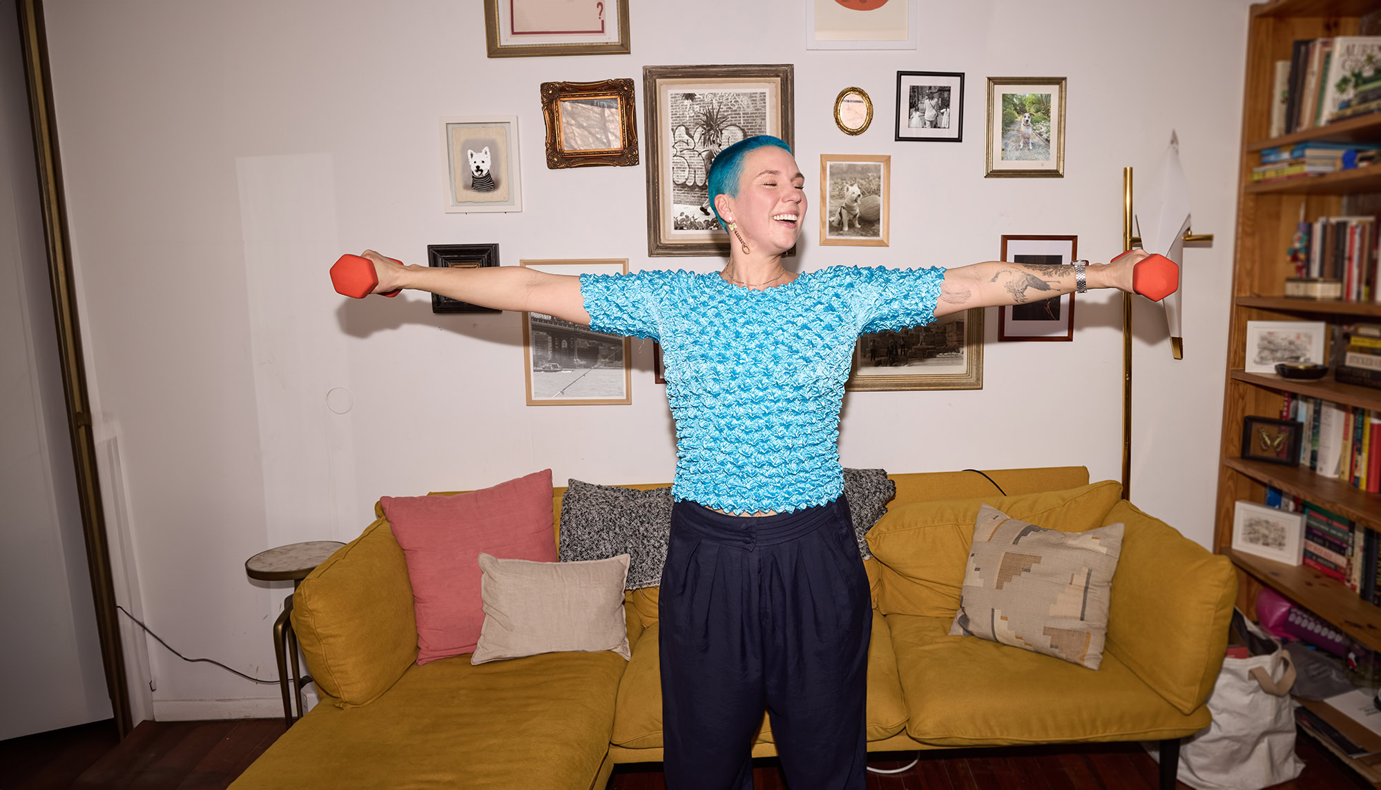 blue haired woman exercises in a living room lifting weights