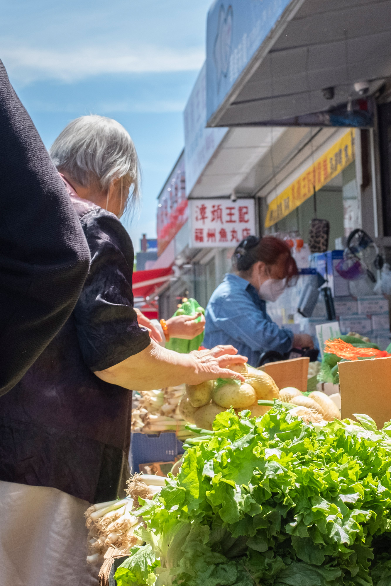 Elderly woman picks produce at an outdoor market