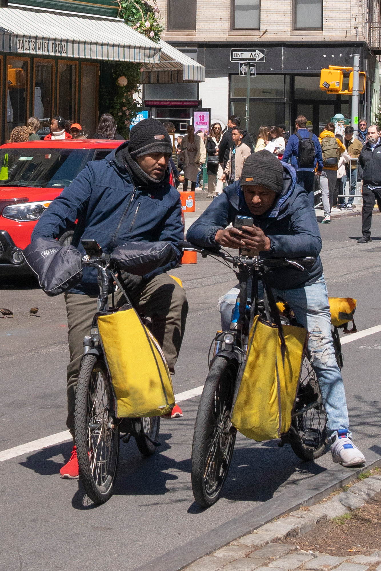 Two bike delivery messengers looking at cell phones looking perplexed