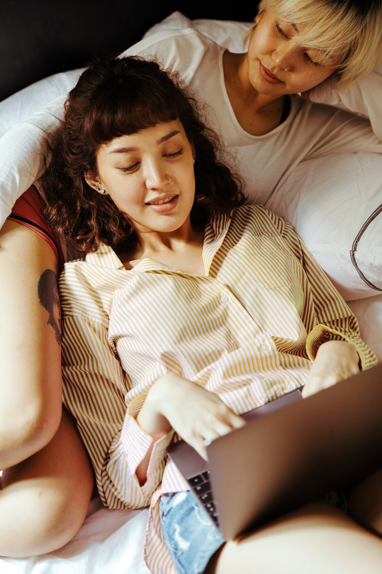 Two women in bed looking at a laptop