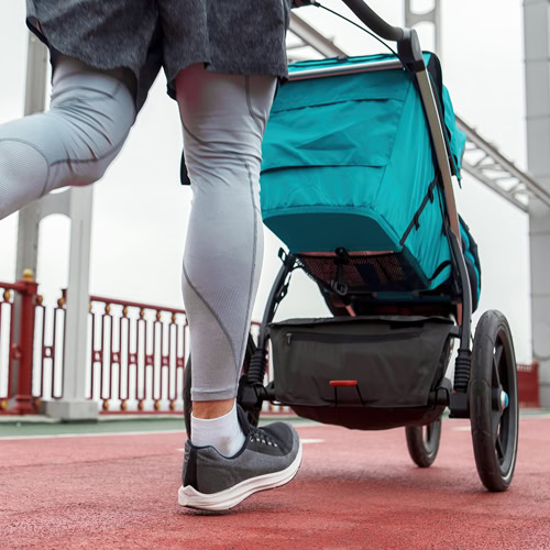 A mother pushes a stroller while jogging