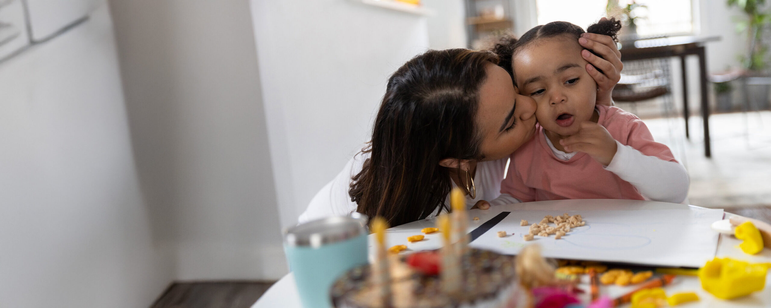 A mother kissing and hugging her child, representing the security of MetroPlusHealth Individual & Family Plans.