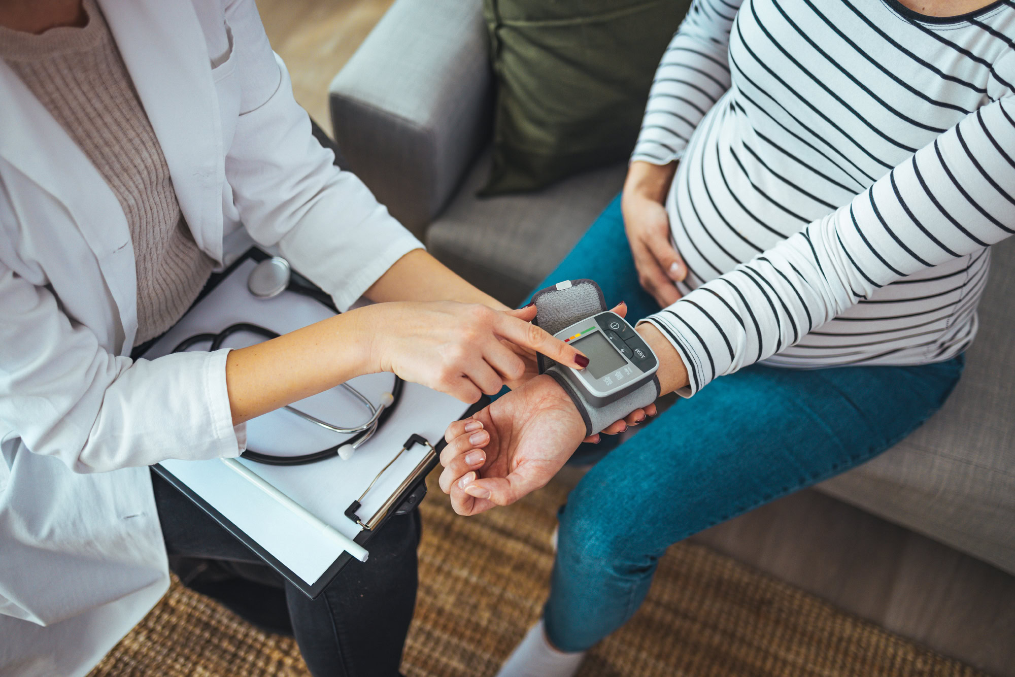 Doctor measuring blood pressure of young pregnant woman, close u