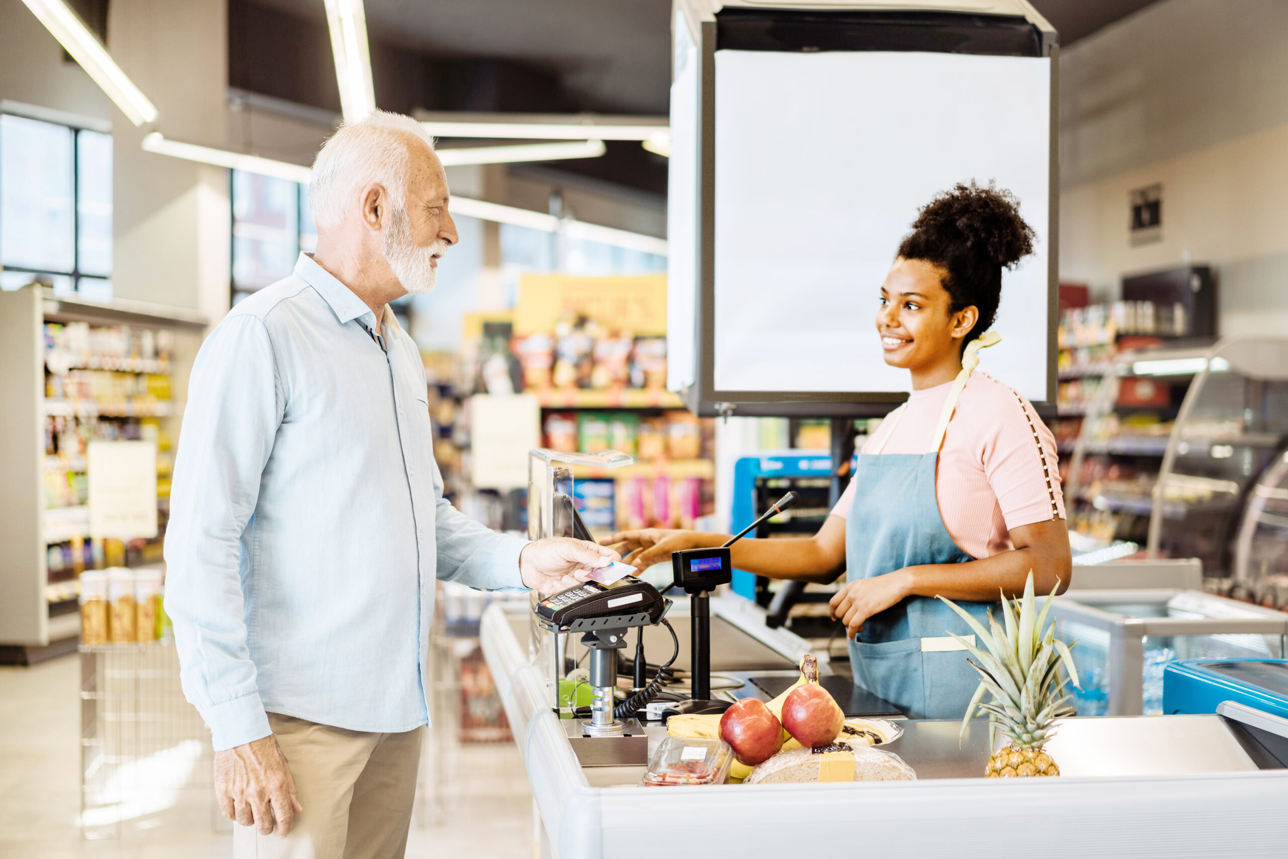 A person using their MetroPlusHealth Flex Rewards Card at a grocery store counter to purchase healthy food and over the counter health products.