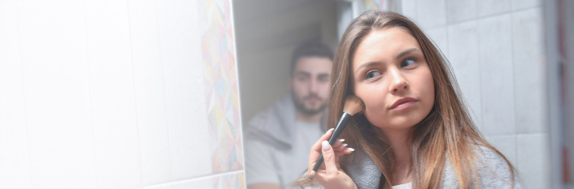 young couple in front mirror in bathroom apply make-up